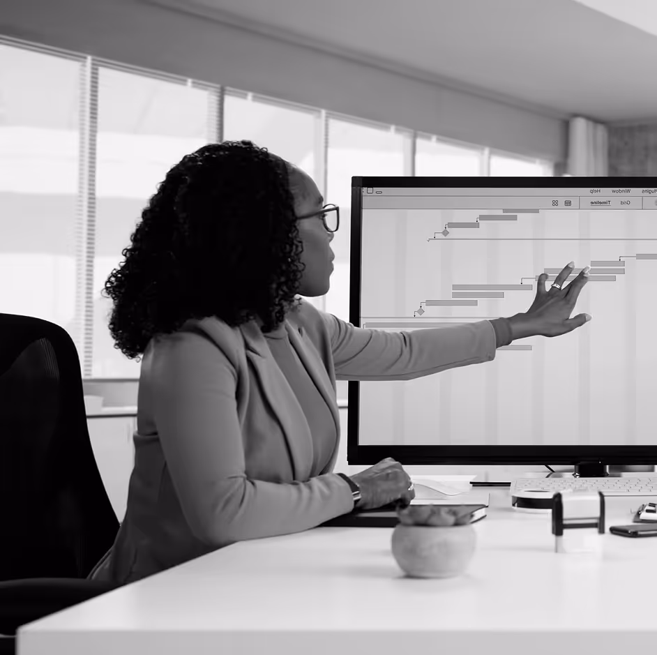 Woman at her desk pointing at analytics on a screen