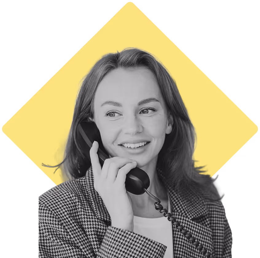 Woman smiling, speaking on a desk phone