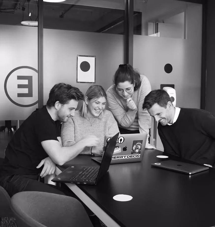 Work team of four looking at a laptop in a conference room