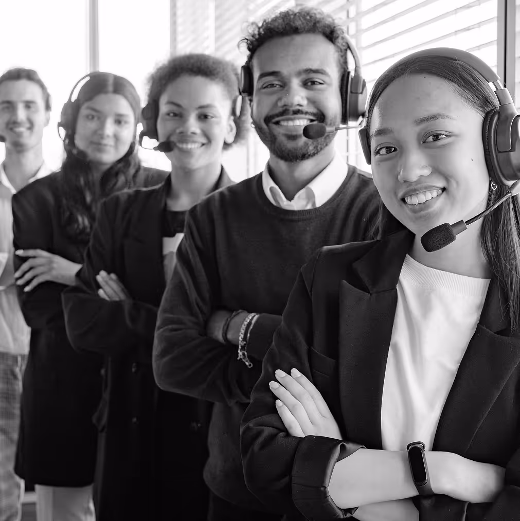 Five employees with head sets, cross-armed, smiling at the camera